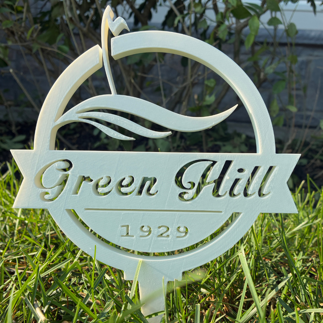 Green Hill 1929 artistic cut-out tee sign with flowing landscape elements and intricate ornamental design in white plastic