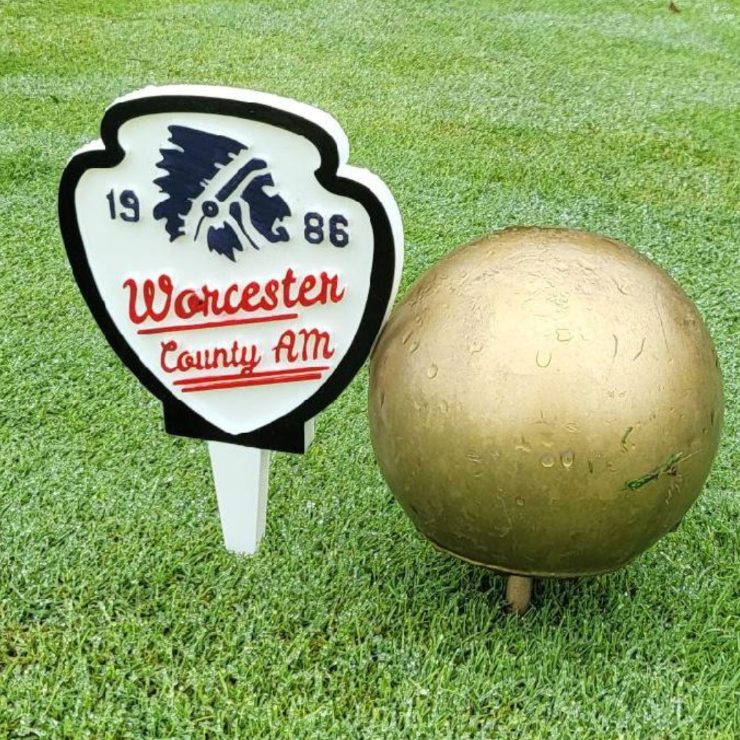 Worcester County AM 1986 shield-shaped tournament tee sign with Native American logo, red script lettering, and professional tournament styling on golf course grass
